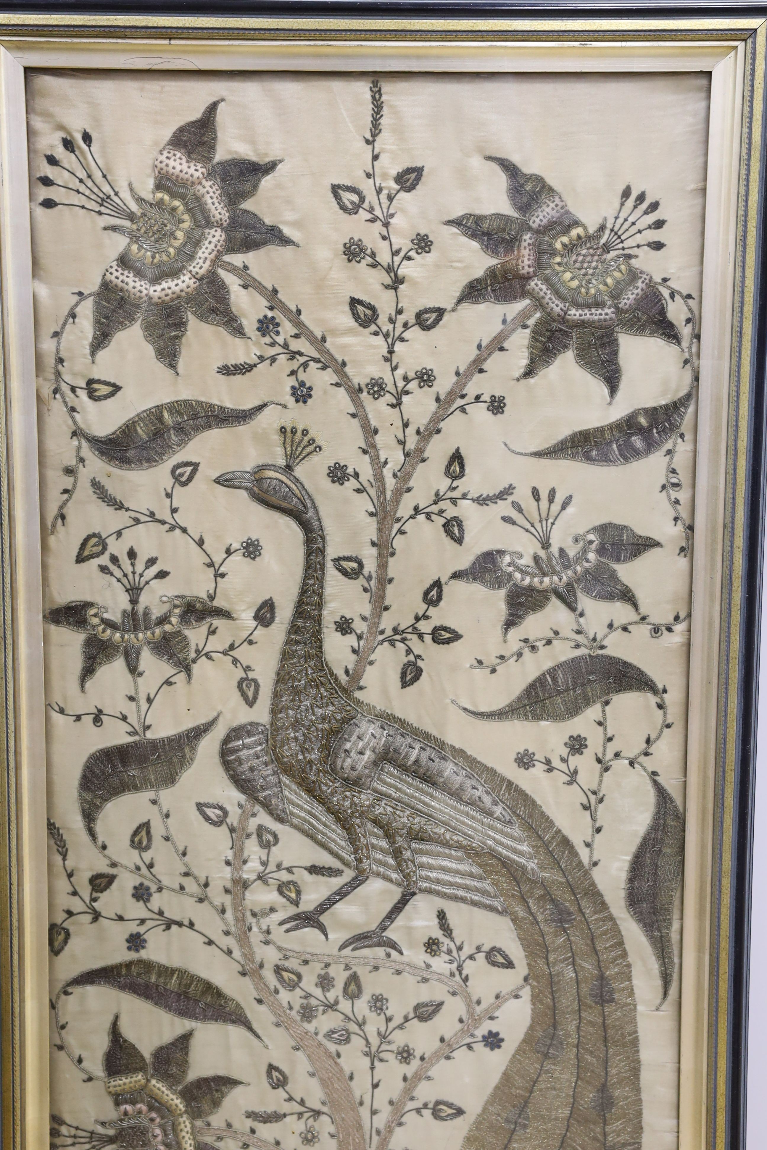 A framed large 19th century Indian embroidered panel decorated with a peacock and flowers 108x49cm